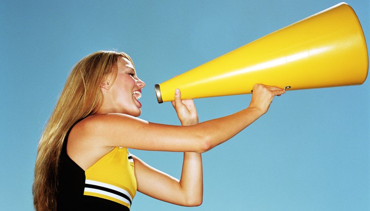 Cheerleader yelling through megaphone, low angle, side view