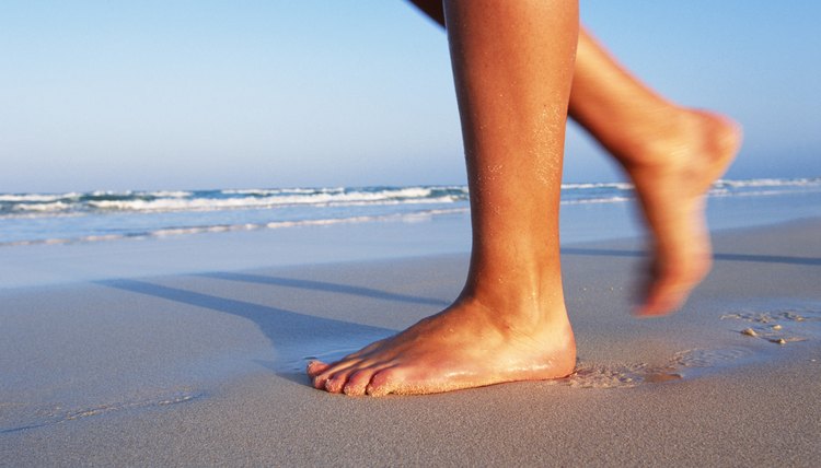 Woman's feet walking on sandy beach, close up