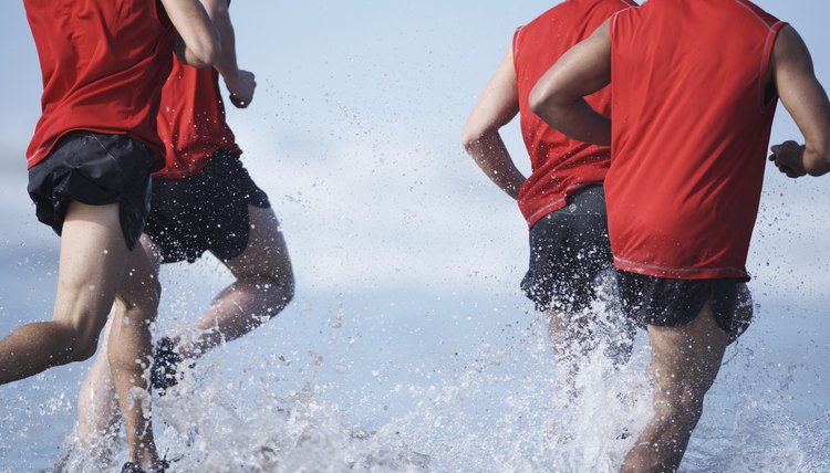Men running in ocean, low section