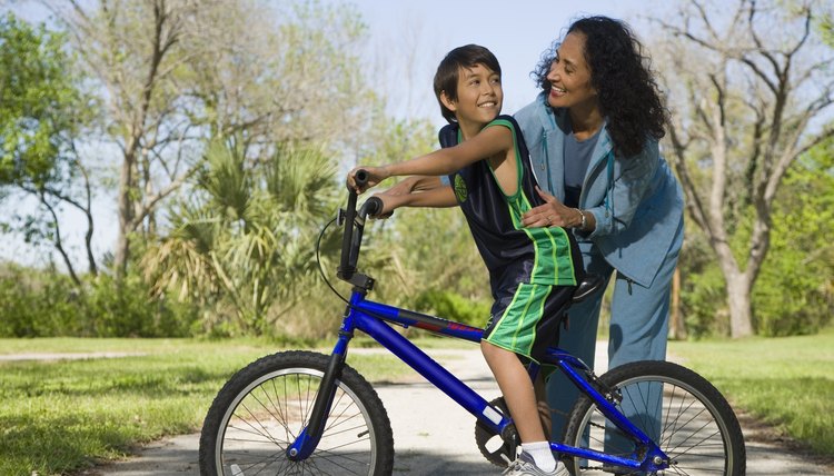 Hispanic mother smiling at son on bicycle