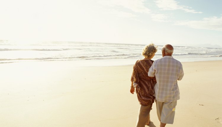 Senior couple walking on beach, rear view