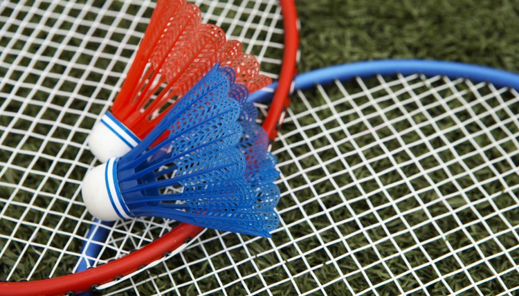 Two shuttlecocks atop badminton rackets (focus on shuttlecock)