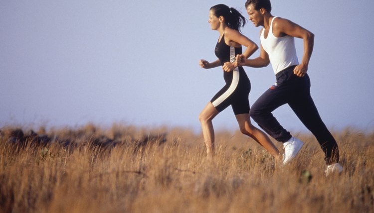 Young couple jogging in field, side view