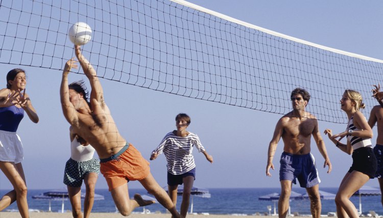 Group of young people playing volleyball on beach