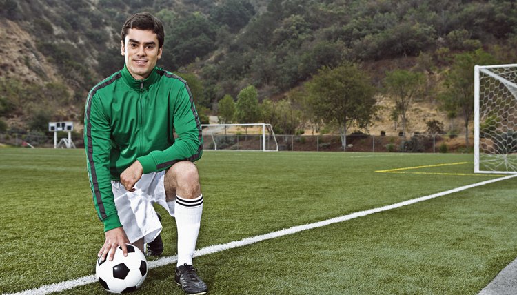 Soccer player posing with ball on field