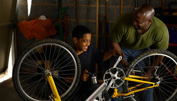 Father and teenager oiling bicycle chain