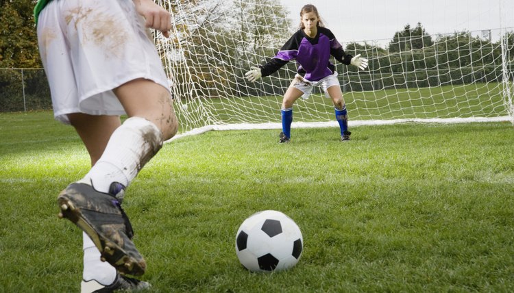 Girl kicking soccer ball toward goal