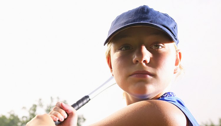 A softball player looking over her shoulder preparing to hit the ball