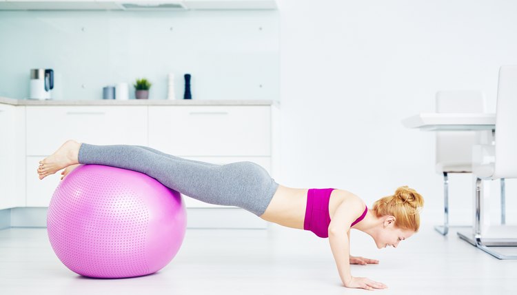 Girl doing push-ups in the kitchen with her legs on fitball