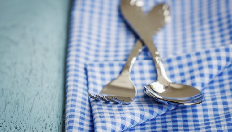 A spoon and fork on a blue tablecloth.