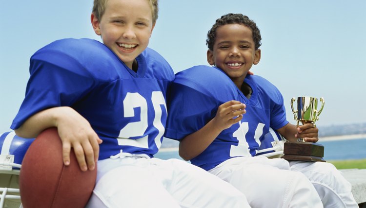 portrait of two boys sitting with a football and a trophy