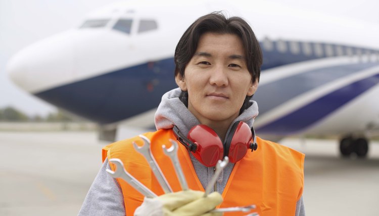 Airport hangar worker on tarmac with wrenches