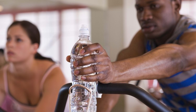 Man reaching for bottled water on exercise bike