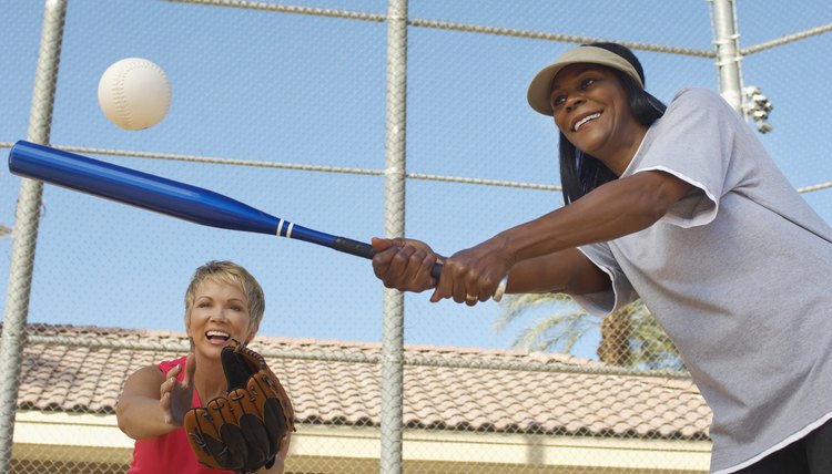 Senior woman hitting softball with other woman catching