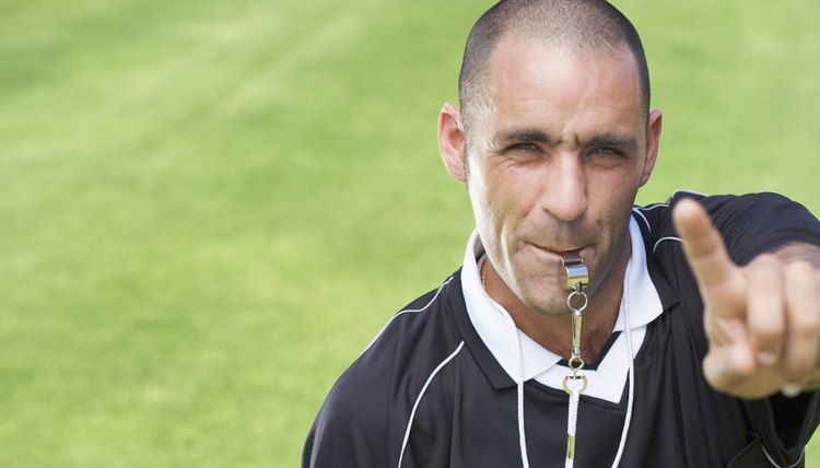 Referee blowing whistle and pointing