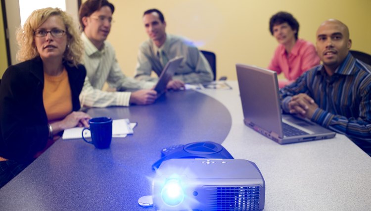 Employees wrapping up a PowerPoint presentation in a conference room.