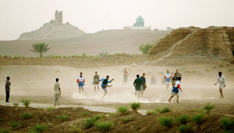 The ruins of a ziggurat built by Nebuchadnezzar rise in the distance behind an Iraqi soccer game.