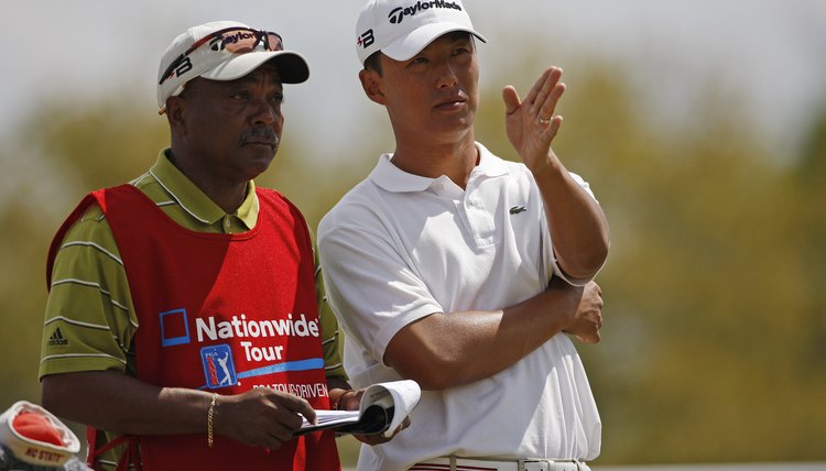 A professional golfer and caddie consulting a yardage book.