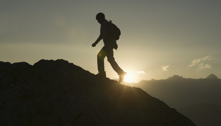 Silhouette of person climbing mountainside