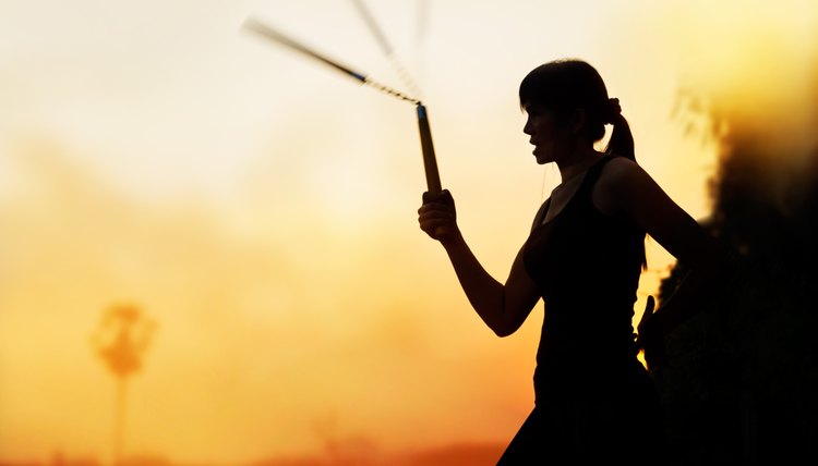 martial arts, women and nunchaku in hands silhouette in sunset