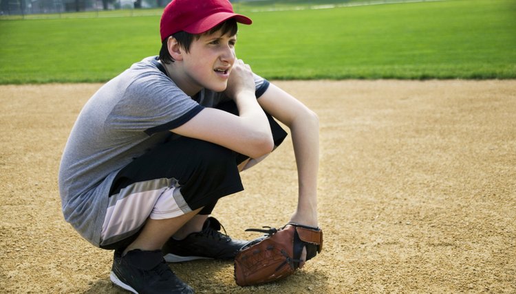 Teenage boy squatting down wearing ball glove