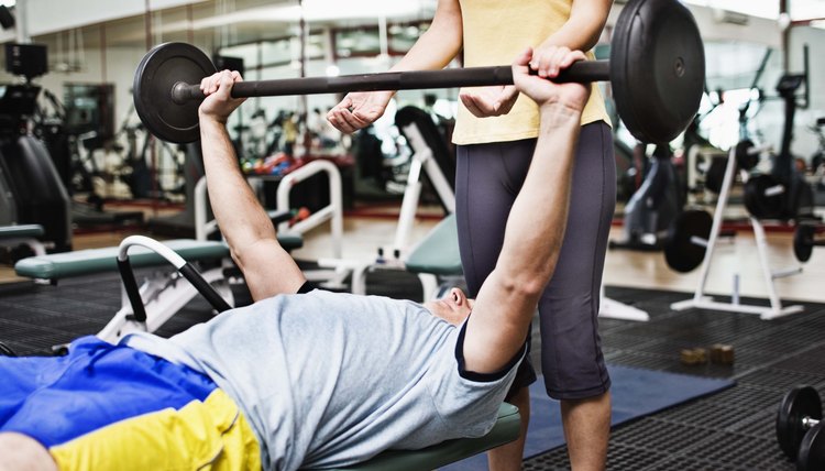 Woman spotting man lifting barbell