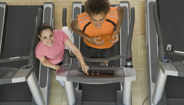 Fitness instructor training man on treadmill in gym, elevated vi