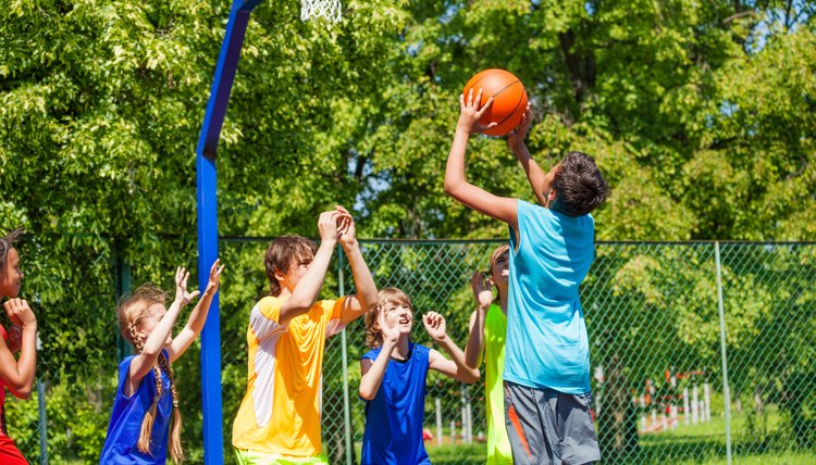 Group of teenagers play basketball on playground