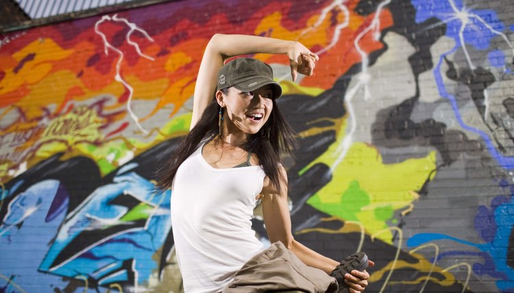 Woman street dancing by graffiti mural