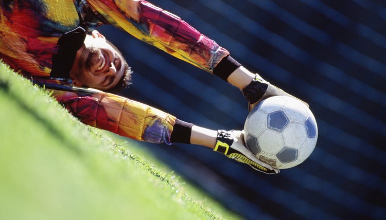 Soccer goalie lunging and catching ball