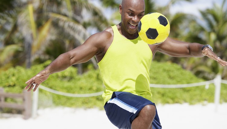 African American man bouncing soccer ball on knee
