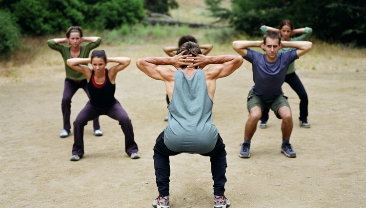Man leading group of people in boot camp exercises, rear view