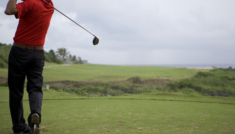 Man swinging golf club, rear view