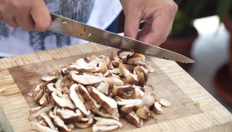 Woman's hands slicing mushrooms.