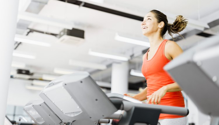 Beautiful young woman running on a treadmill in gym