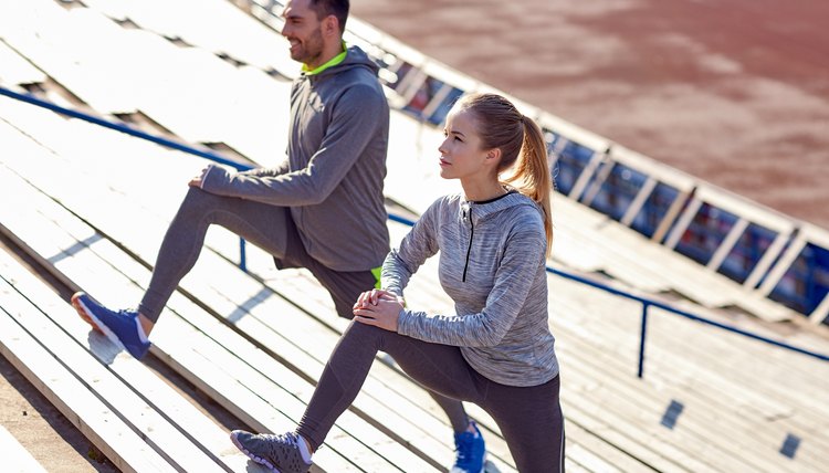 couple stretching leg on stands of stadium