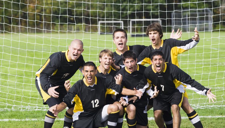Soccer players cheering in front of a goal post in a soccer field