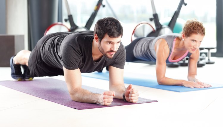 Portrait of a man and woman training together at the gym. Personal trainers doing push ups at the fitness club.