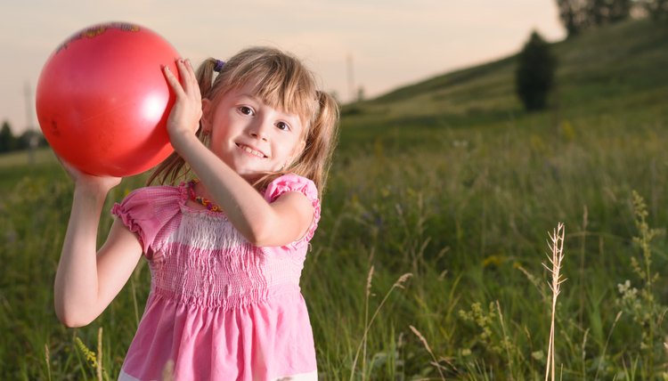 Girl playing with a red ball in the park
