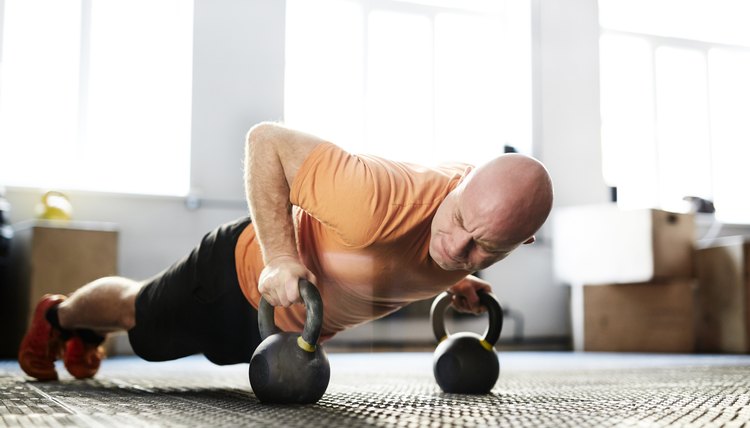 Muscular athlete pushing up with kettlebells