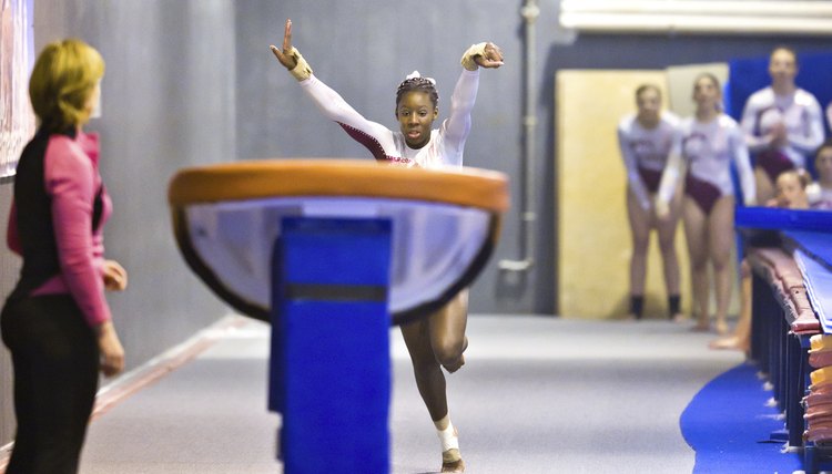 Teammates and Coach Watch Gymnast Performing Vault