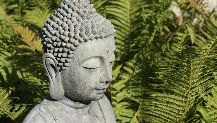 A Buddha statue in the garden with elongated ear lobes.