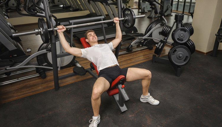 Young man doing Barbell Incline Bench Press workout in gym