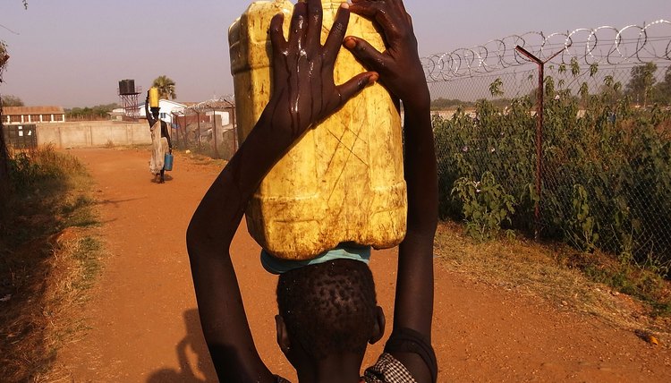 A boy carries water at a refuge camp for impoverished citizens in Sudan.