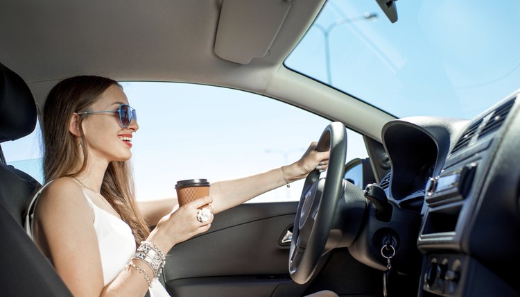Woman drinking coffee in her car while driving.