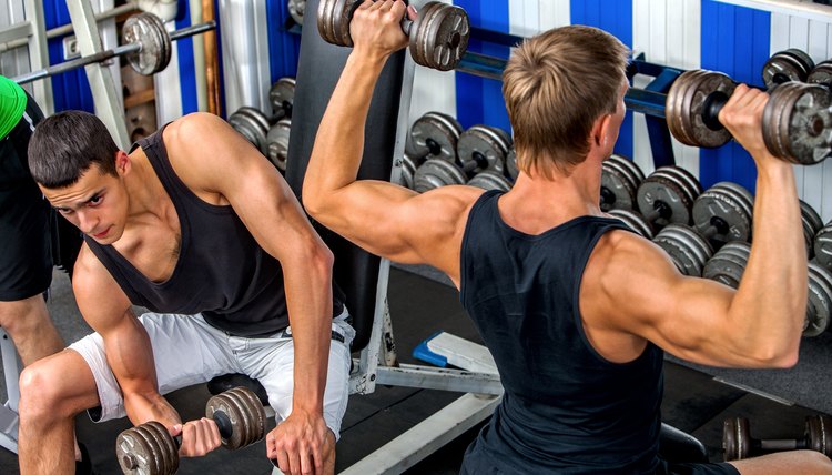 Group of men working with dumbbells  at gym