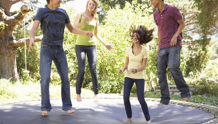 Four Teenage Friends Jumping On Trampoline In Garden