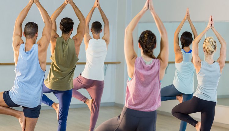 Group of people performing yoga in gym