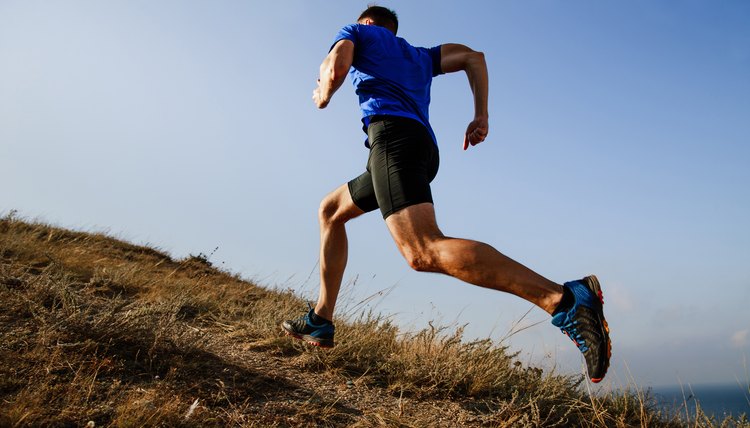 dynamic running uphill on trail male athlete runner side view