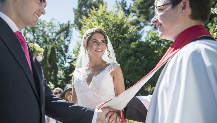 What Does It Mean To Be Ordained Career Trend A Bride And Groom Stand In Front Of Vicar At An Outdoor Wedding